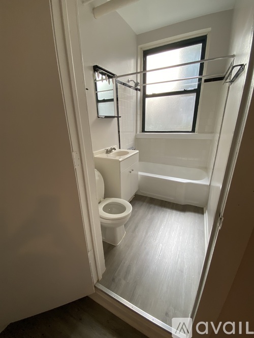 A spacious, empty room with a ceiling fan and a window.