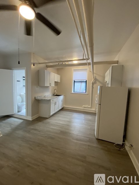 A spacious, empty room with a ceiling fan and a window.
