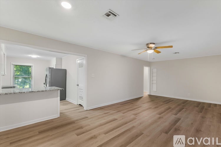 A spacious room with wooden flooring and a ceiling fan.