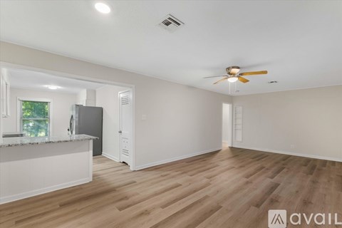 A spacious room with wooden flooring and a ceiling fan.