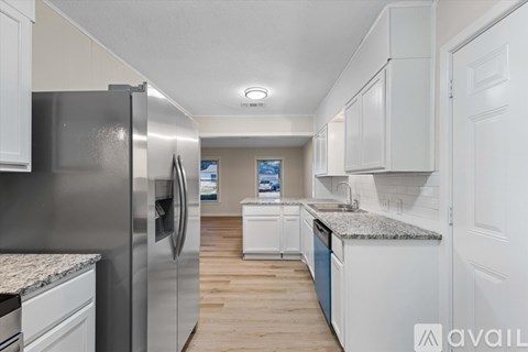 A kitchen with a refrigerator on the left and cabinets on the right.