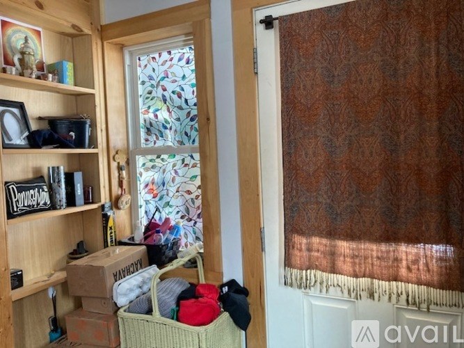 A room with a window covered by a brown curtain and a shelf with various items on it.