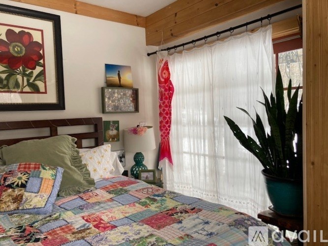 A bedroom with a quilted bedspread and a red curtain.