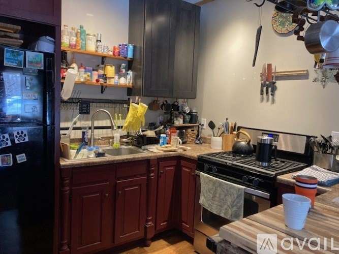 A kitchen with dark wood cabinets and a black fridge.