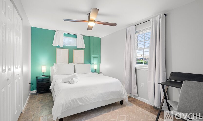 A bedroom with a white bed and a ceiling fan.