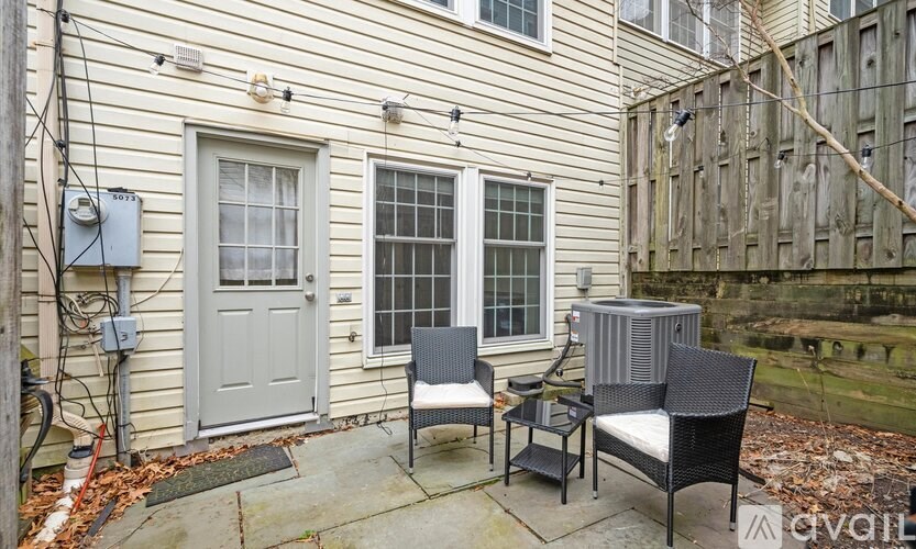 A patio with a grey door, two chairs and a table.