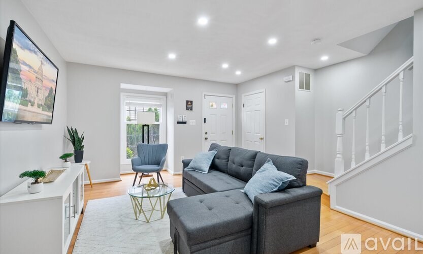 A living room with a grey couch and a white kitchen area.
