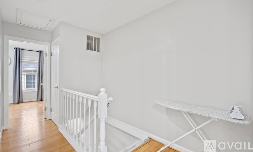 A white room with a window and a white ironing board.