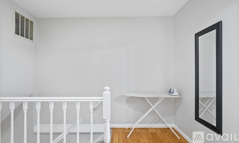 A white room with a staircase, a table, and a mirror.