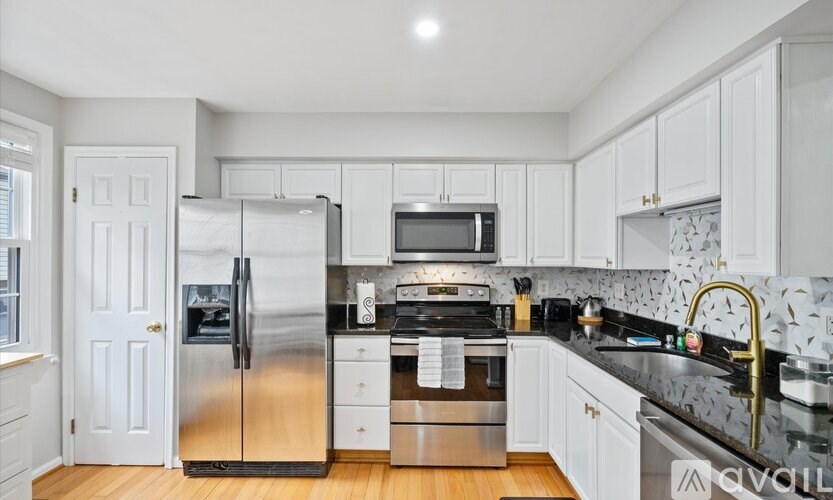 A kitchen with white cabinets and a black countertop.