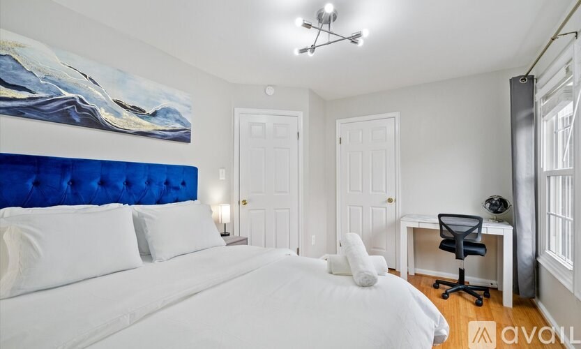 A bedroom with a large bed and a painting on the wall.