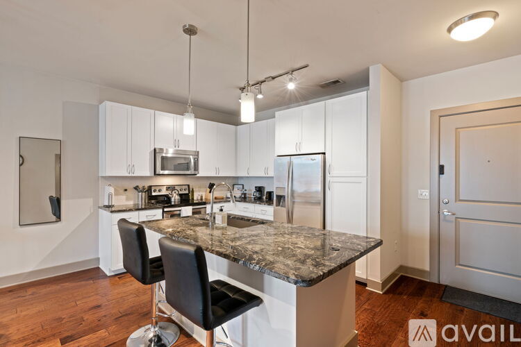 A modern kitchen with a granite countertop and black barstools.