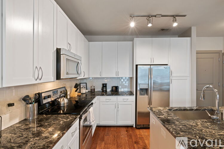 A kitchen with white cabinets and black countertops.