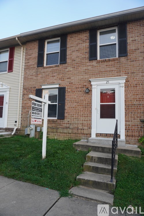 A red brick house with a for rent sign in front.