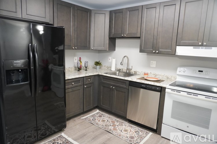 A kitchen with a black refrigerator and white appliances.
