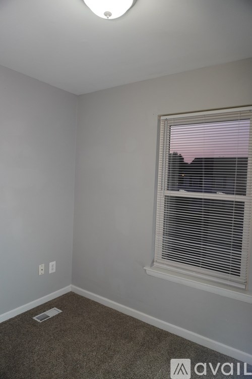 A room with a window and a carpeted floor.