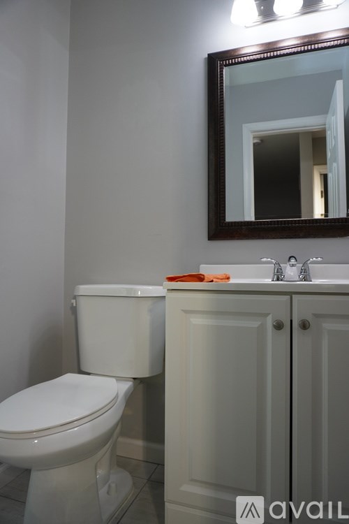A bathroom with a toilet, sink, and mirror.