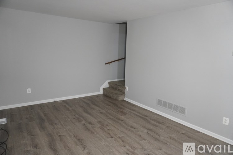 A room with wooden flooring and a staircase leading to the upper floor.