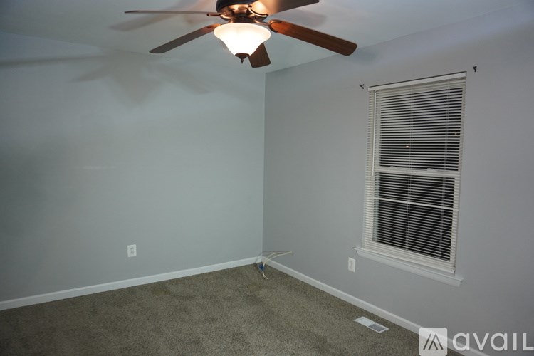 A room with a ceiling fan and a window with blinds.
