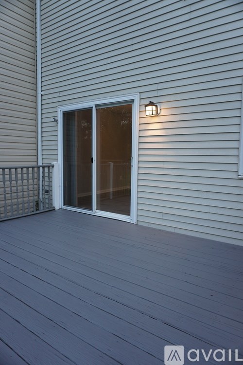 A deck with a sliding glass door and a wall light.