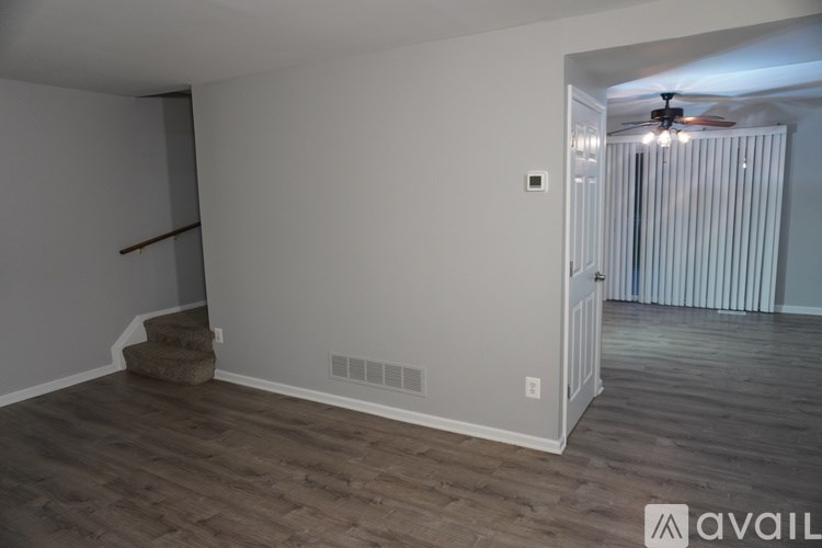 A room with wooden flooring and a staircase leading to another room.