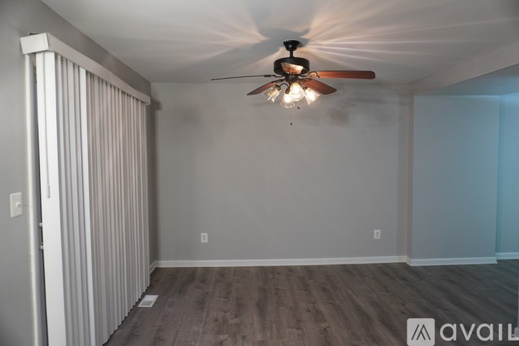 A room with a ceiling fan and light fixture, and a wall with a window.