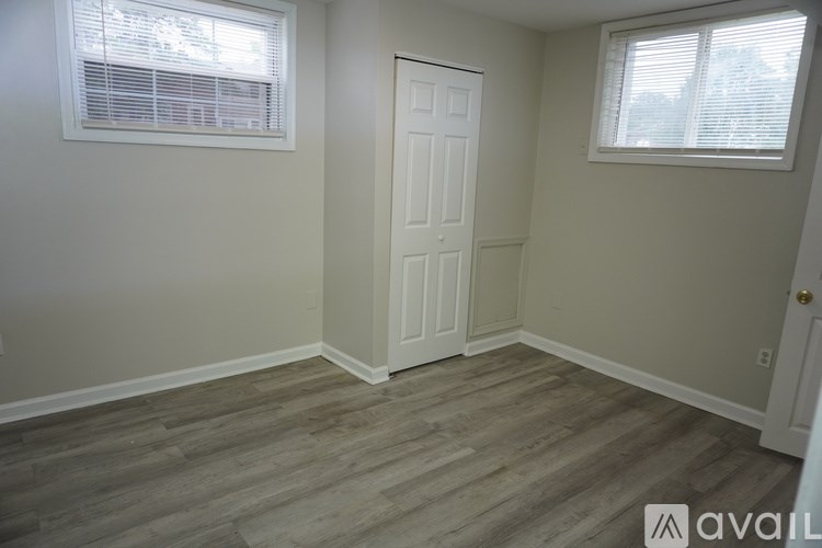 A room with a white door and two windows with blinds.