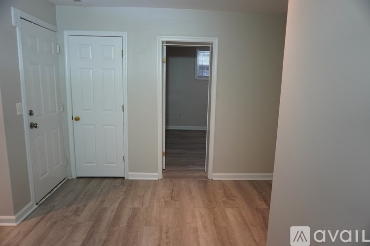 A room with a white door and a wooden floor.