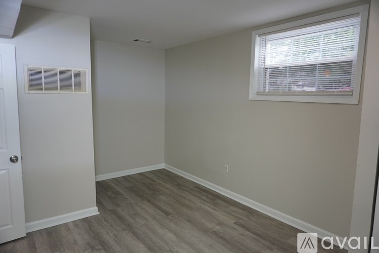 A room with a door, window, and wooden flooring.