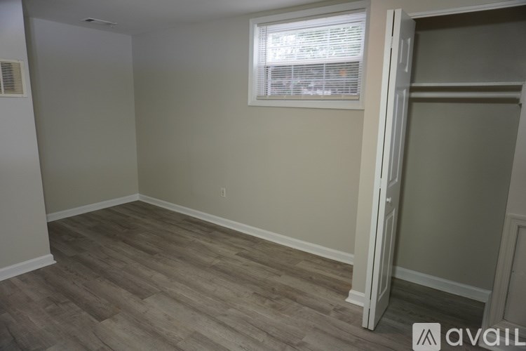 A room with a wooden floor and a window with blinds.