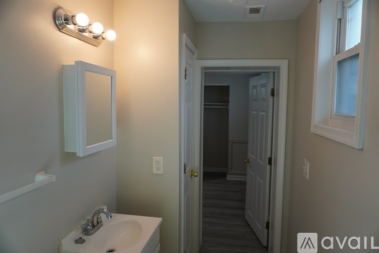 A bathroom with a sink, mirror, and light fixture.