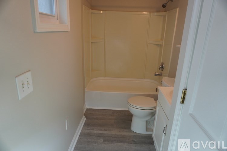 A small bathroom with a toilet, tub, and a door.