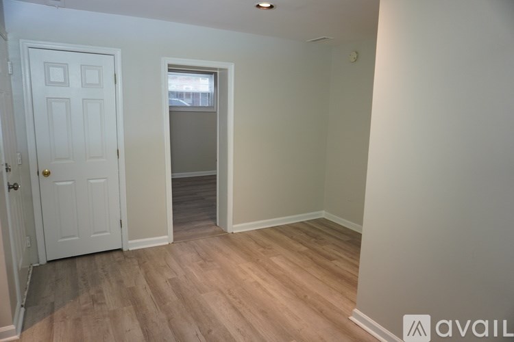 A room with a white door and wooden flooring.