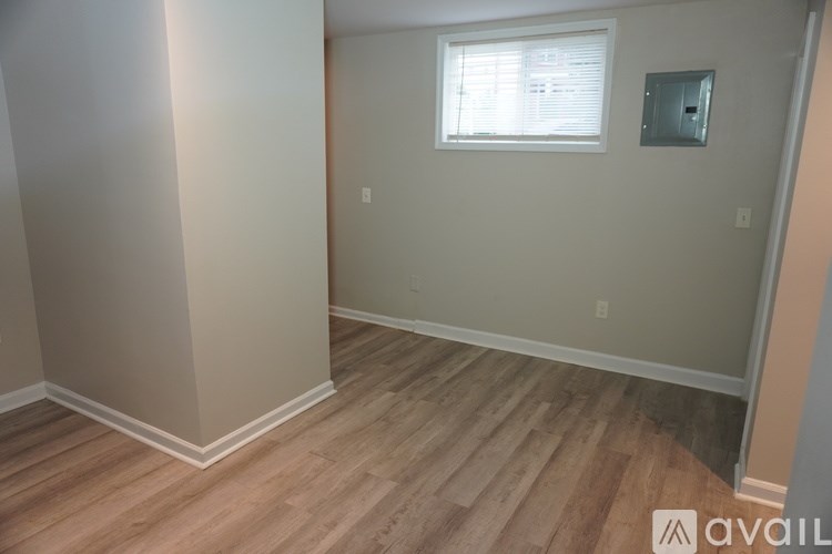 A room with wooden flooring and a window with blinds.