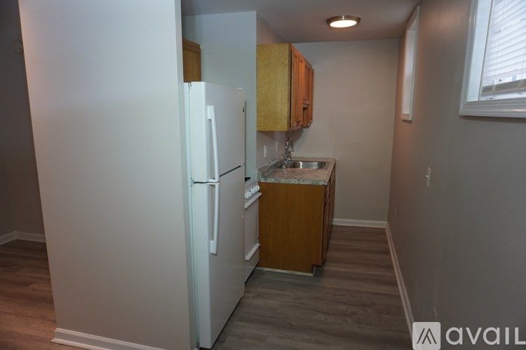 A small kitchen with a white refrigerator and wooden cabinets.
