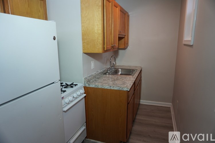A kitchen with a white fridge, wooden cabinets, and a marble countertop.