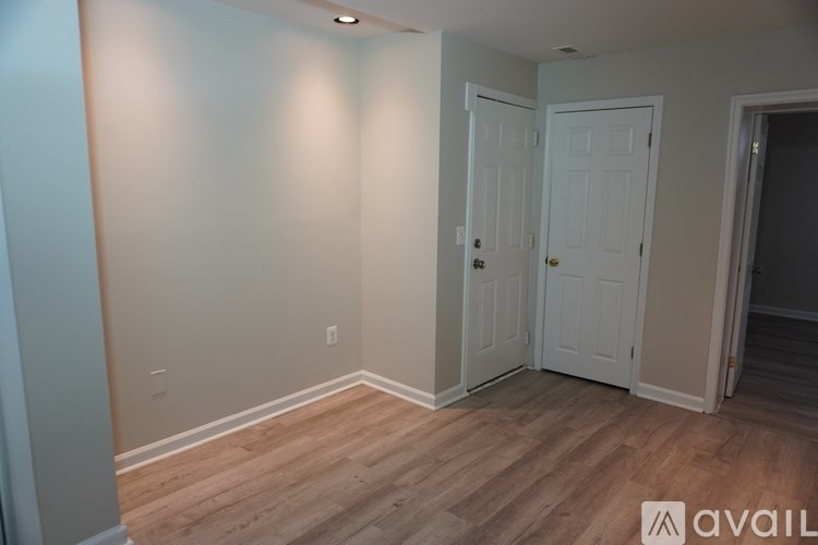 A room with a white door and wooden flooring.