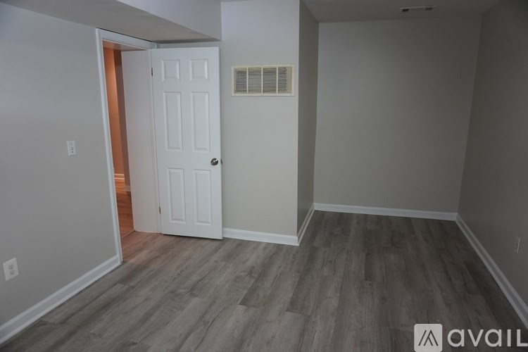 A room with a white door and wooden flooring.