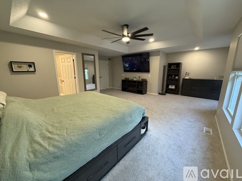 A bedroom with a bed, a ceiling fan, and a television.