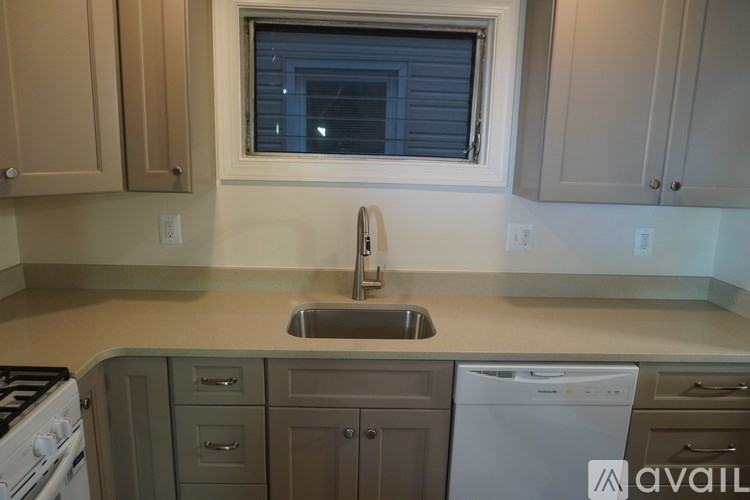A kitchen with a stove, sink, and cabinets.