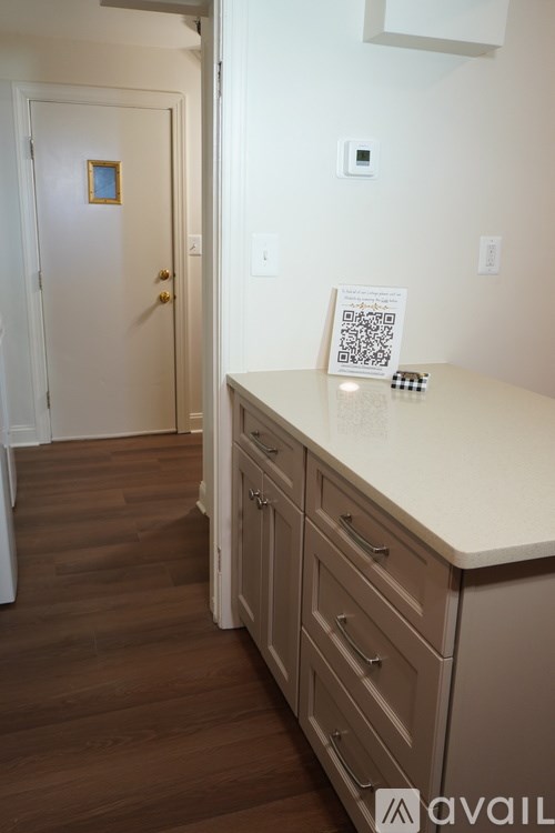 A white door with a gold handle is in a room with a white wall and a wooden floor.