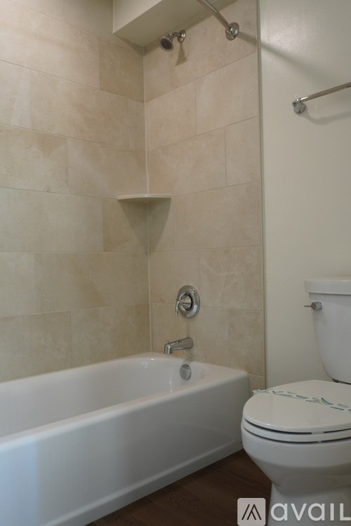 A white bathtub with a shower head and a toilet in a bathroom.