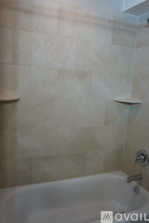 A bathroom with a white bathtub and tiled walls.