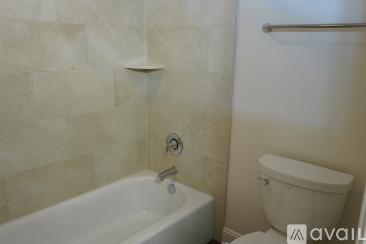A white bathtub with a shower head and a toilet in a bathroom.