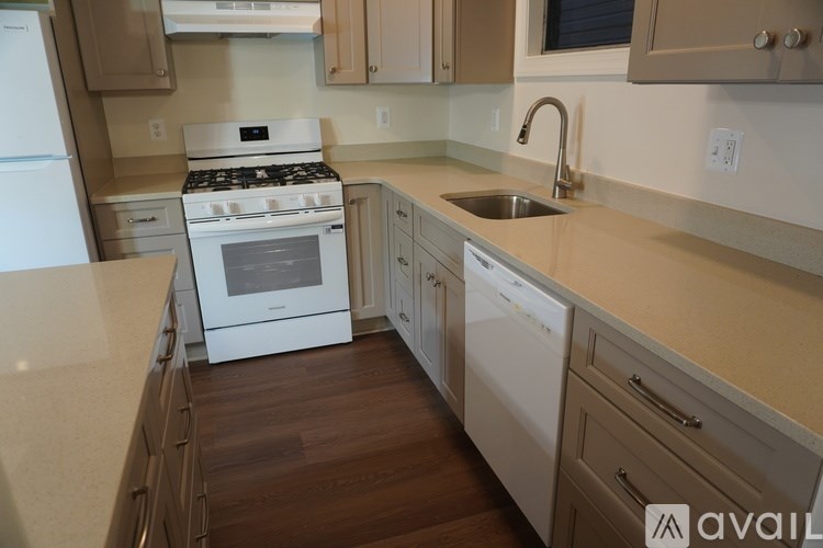 A kitchen with a white stove top oven and a white dishwasher.