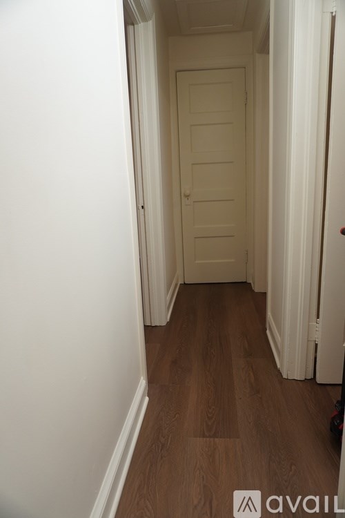 A hallway with a white door and wooden floor.
