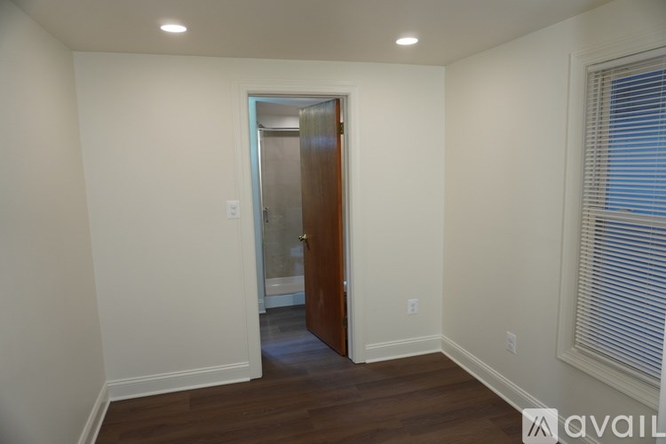 A room with a wooden door and a window with blinds.