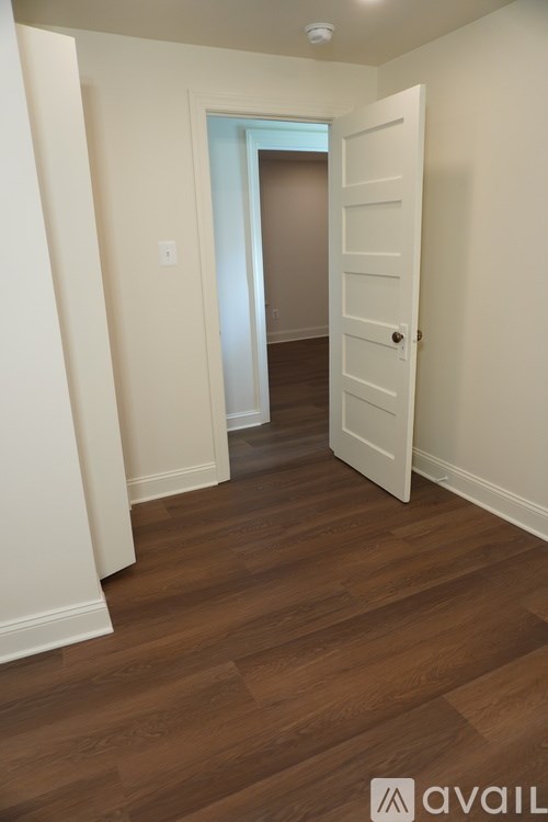 A hallway with a white door and wooden floors.