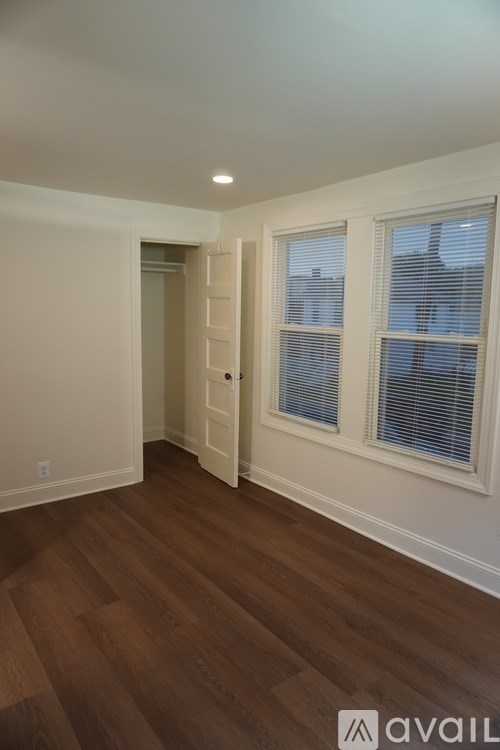 A room with wooden floors and a window with blinds.