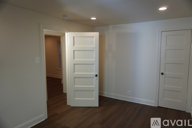 A room with a white door and wooden floor.